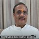 Video still of Professor Dr. Dinesh Sharma, MP (Rajya Sabha) and former Uttar Pradesh Deputy Chief Minister, seated in a white kurta, with event logos in the background.