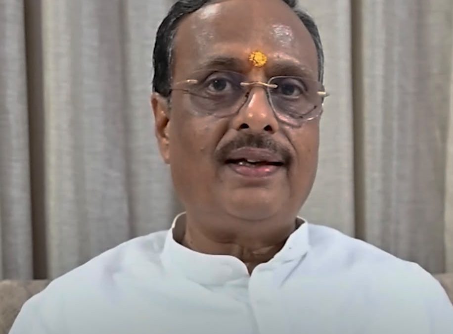 Video still of Professor Dr. Dinesh Sharma, MP (Rajya Sabha) and former Uttar Pradesh Deputy Chief Minister, seated in a white kurta, with event logos in the background.