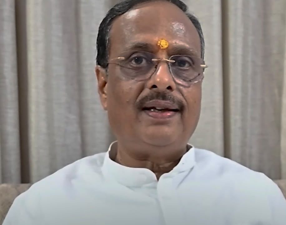 Video still of Professor Dr. Dinesh Sharma, MP (Rajya Sabha) and former Uttar Pradesh Deputy Chief Minister, seated in a white kurta, with event logos in the background.