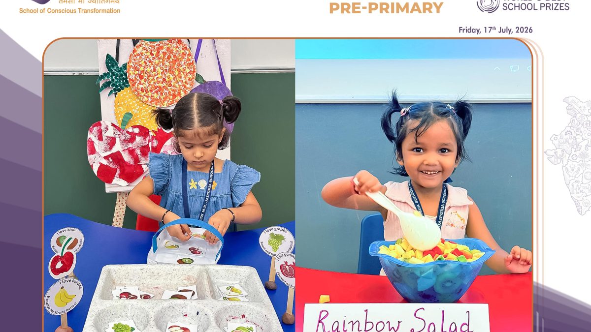 Two young girls participate in a fruit-themed classroom activity with labeled fruit cards at a Rainbow Salad station during Fruit Awareness Day.