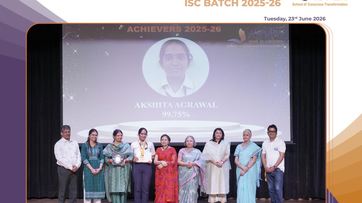 Group of award recipients and staff posing on stage after a felicitation ceremony, some holding certificates and a trophy