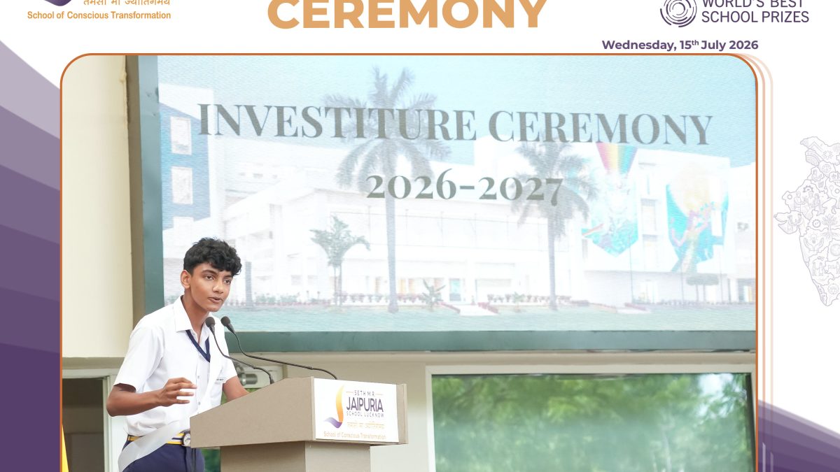 Boy in white shirt speaks at podium during school investiture ceremony; banner behind reads 'Investiture Ceremony 2026-2027' with school logos nearby.