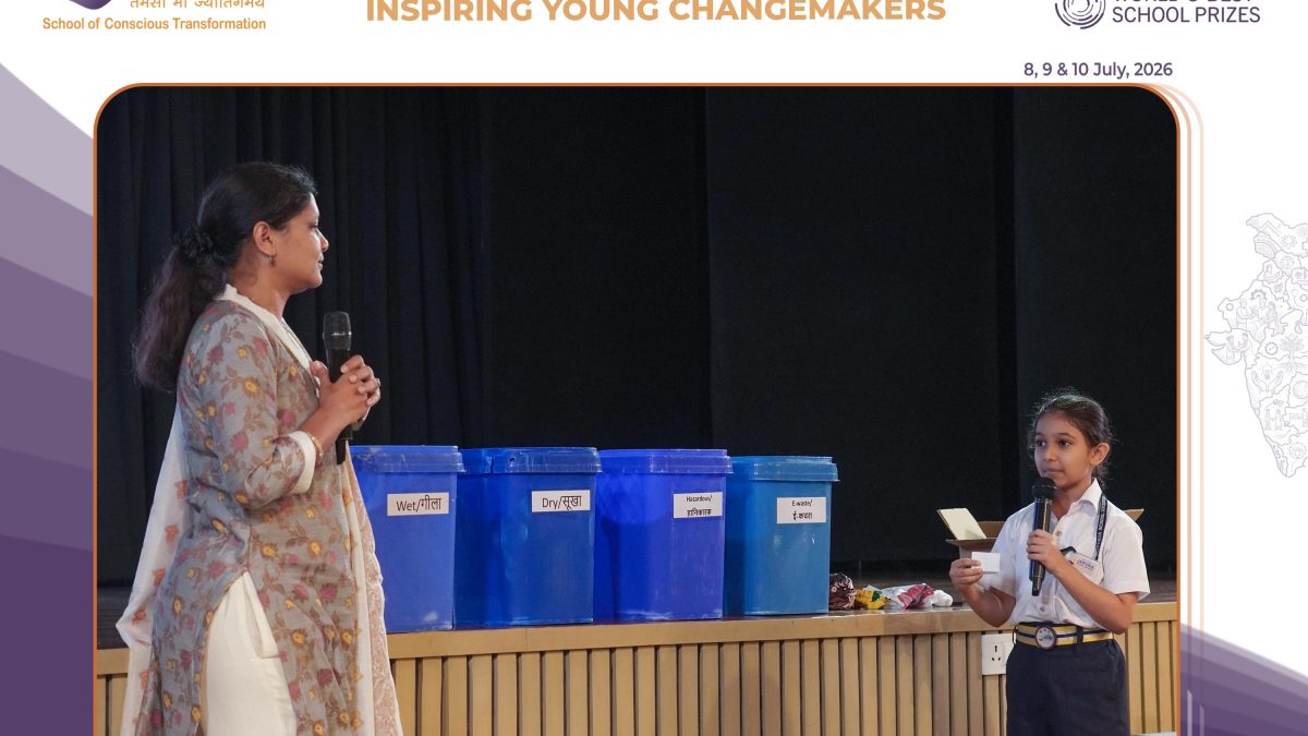 Woman speaks into a microphone on stage beside blue labeled recycling bins at a sustainability workshop.