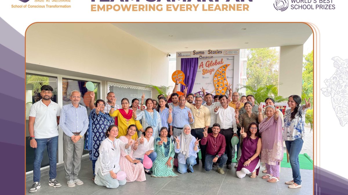 Group of students and teachers posing for a photo at a school event, some making peace signs and holding balloons outdoors.