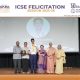 Group of students and seniors on a stage during an ICSE Felicitation ceremony, posing with medals and certificates.