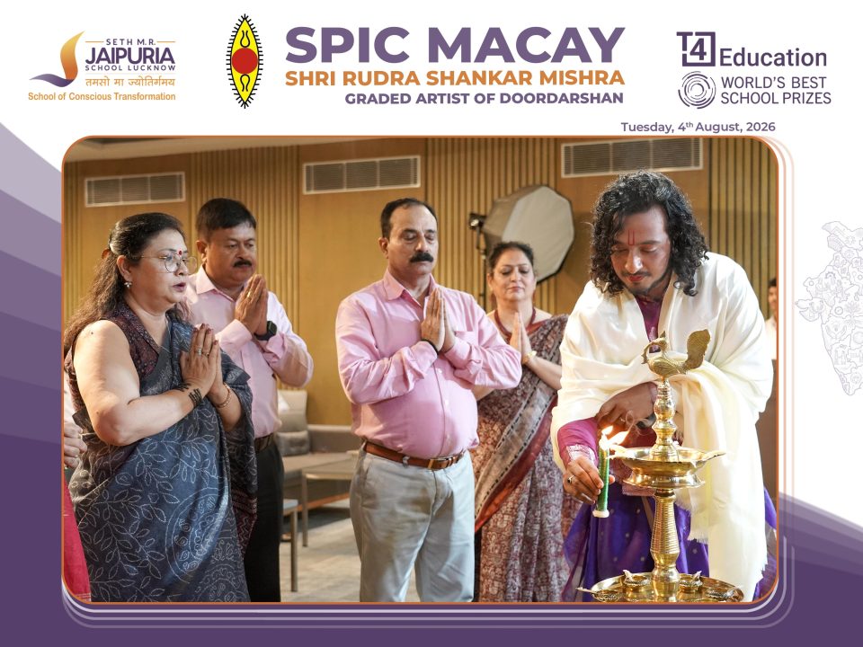 Group of adults praying during a ceremonial lamp-lighting led by a priest holding a lit brass lamp.