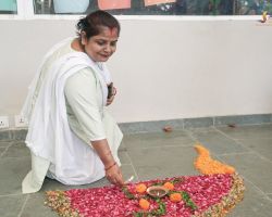 One of our support staff members placing a diya on the rangoli