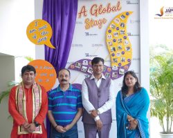 Four adults pose for a photo at a school event in front of a decorative backdrop with 'A Global Stage' text and purple curtains.