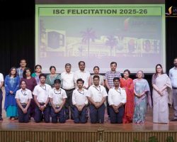 Group of students and teachers posing on a stage during a school felicitation event, with a banner reading 'ISC FELICITATION 2025-26' in the background